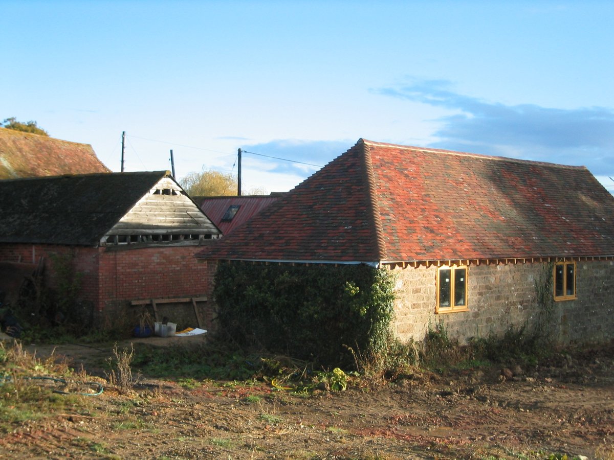 Original red brick barns before conversion — West Sussex heritage site, land restoration project