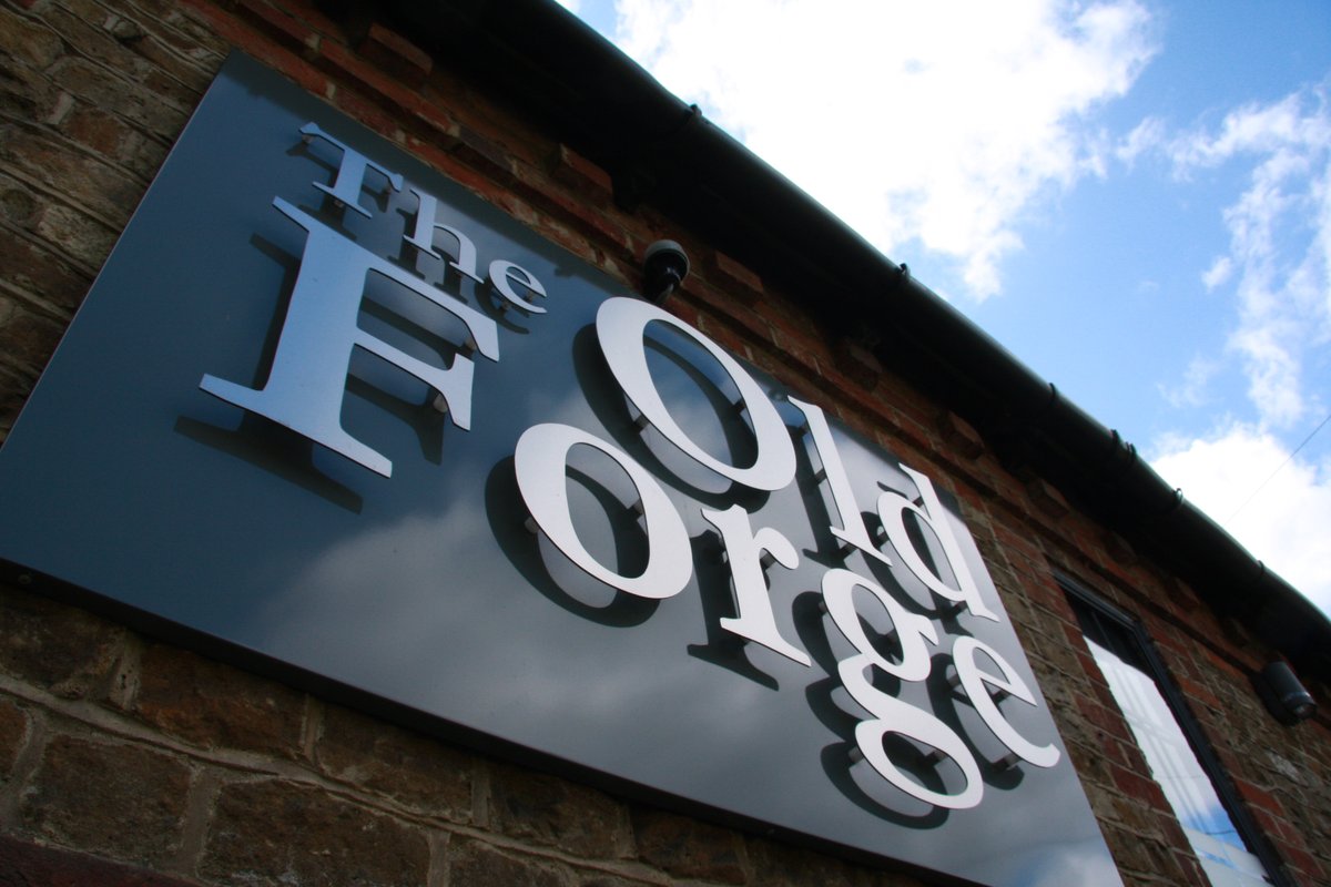 The Old Forge brushed-metal signage on original brickwork — Godalming office conversion