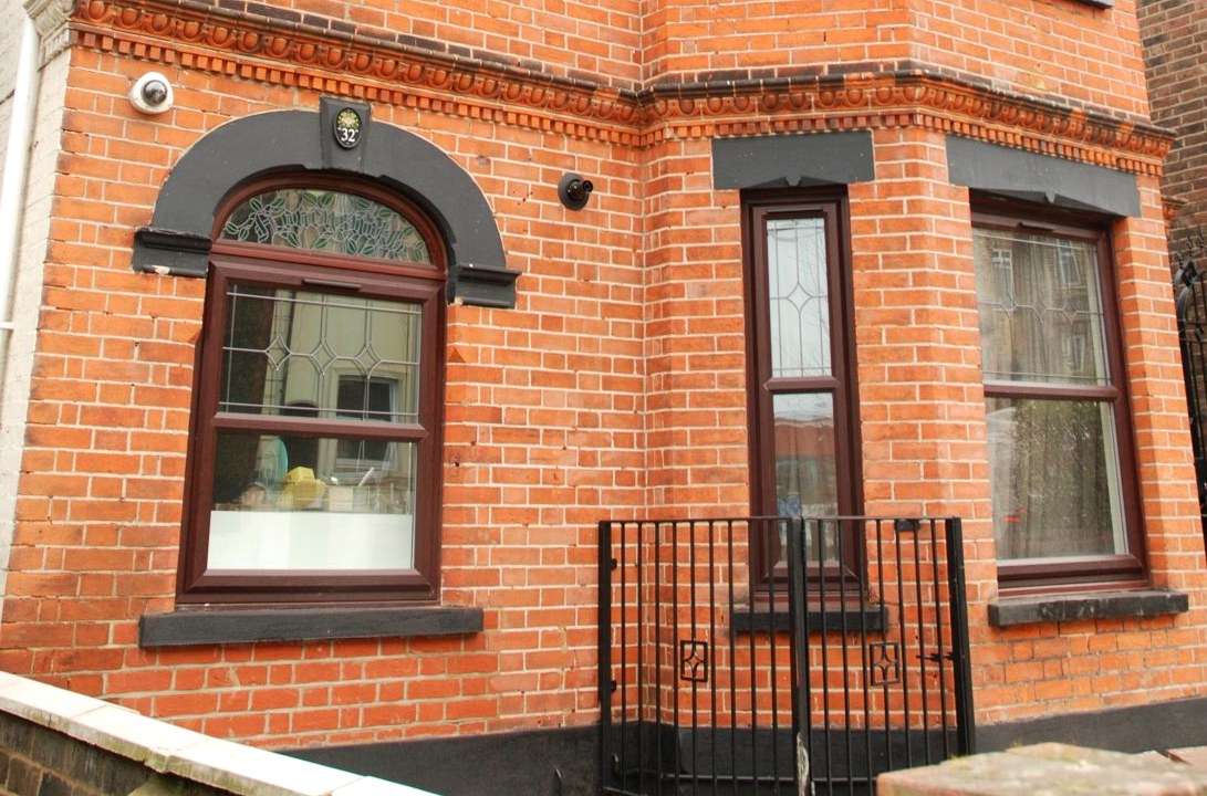 Preserved Victorian facade detail — cogged brickwork, arched window heads, period ironwork, Surrey
